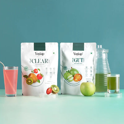 Yugap clear and gut packages with a glass of pink juice and green apple on a teal background